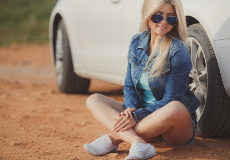 Blonde Frau sitzt vor einem Auto
